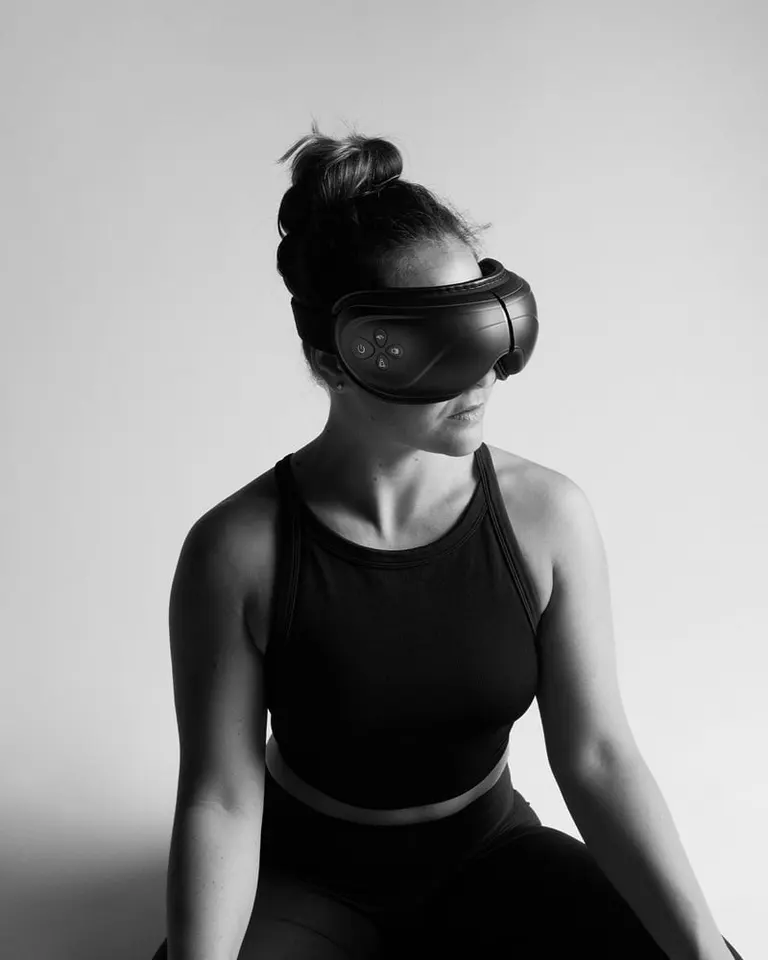 Woman wearing black Flowpression Goggles, an eye massager designed for tension relief and restorative recovery.