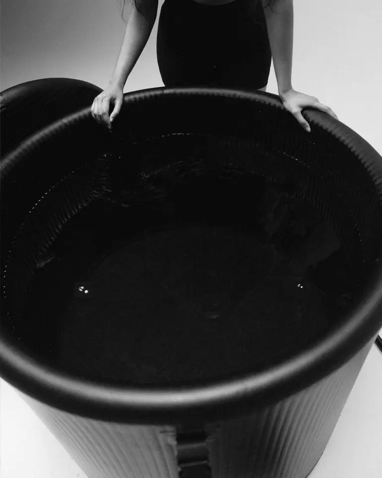 Top view of the black Flowplunge Pro cold plunge tub with reinforced walls, showing a person's hands on the rim.