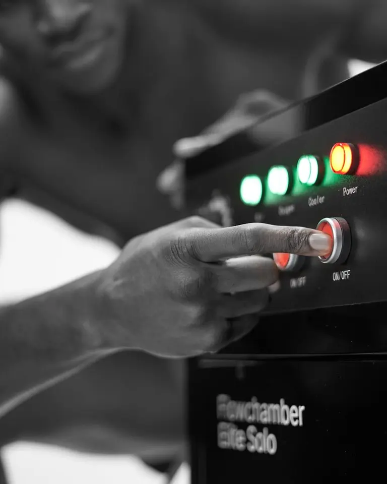 Close-up of a hand operating the Flowchamber Oxygen Elite 170 Soft-Shell control unit with illuminated status indicators.